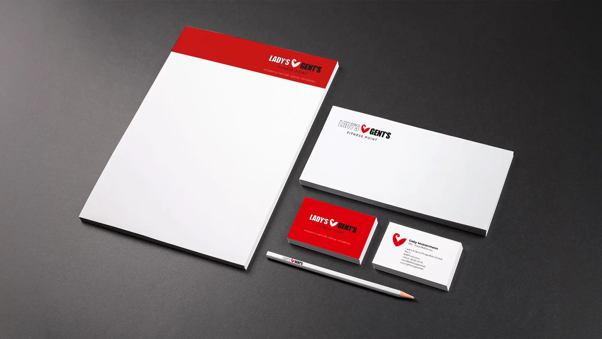 Geschäftsausstattung von Lady’s & Gents Fitness Point mit Briefbogen, Visitenkarten, Umschlag und Bleistift im rot-weißen Corporate Design.
