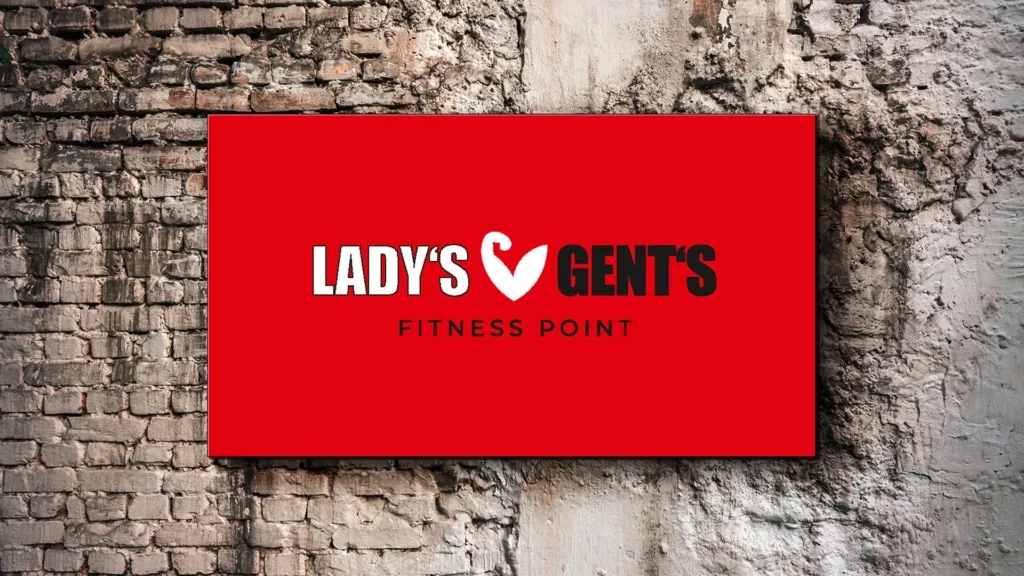 Rotes Schild mit dem Logo von Lady’s & Gents Fitness Point an einer Backsteinwand als Ergebnis der Logo-Entwicklung.
